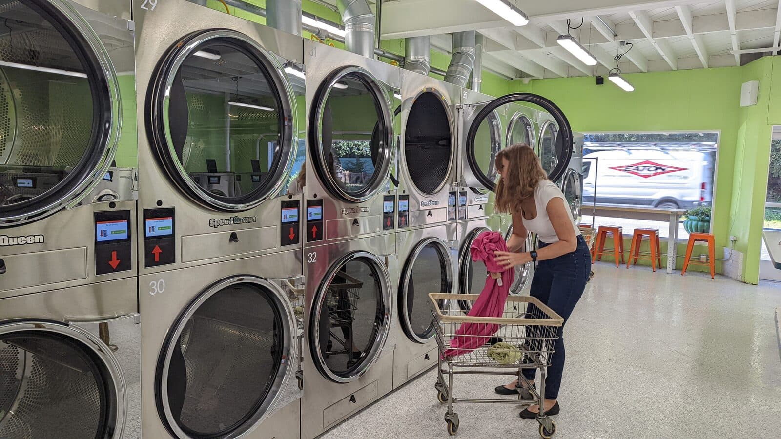 A customer wheeling a laundry cart to the large washers at The Mat