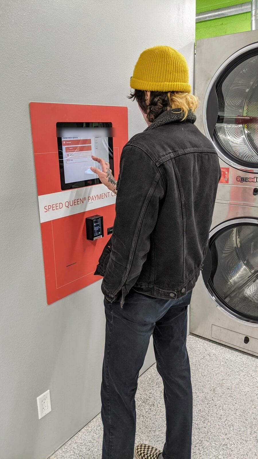 A customer using the Speed Queen payment centre on the wall inside The Mat