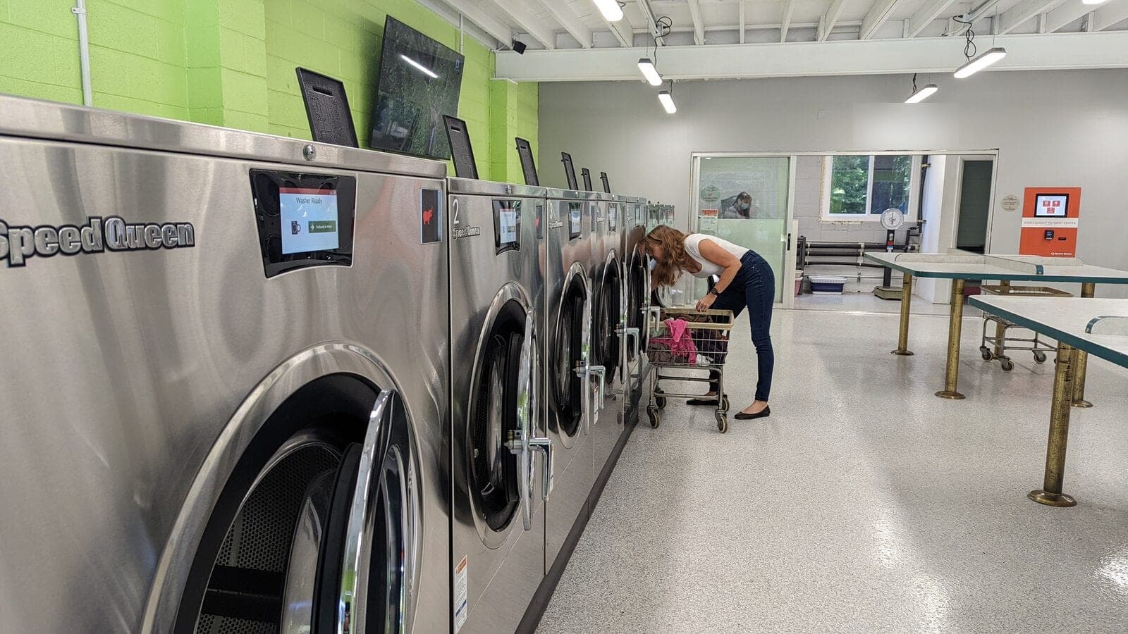 A customer loading one of the large Speed Queen washer extractors from a cart