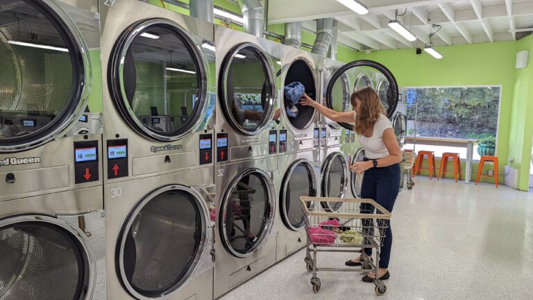 A Woman Placing Clothes in a Laundromats